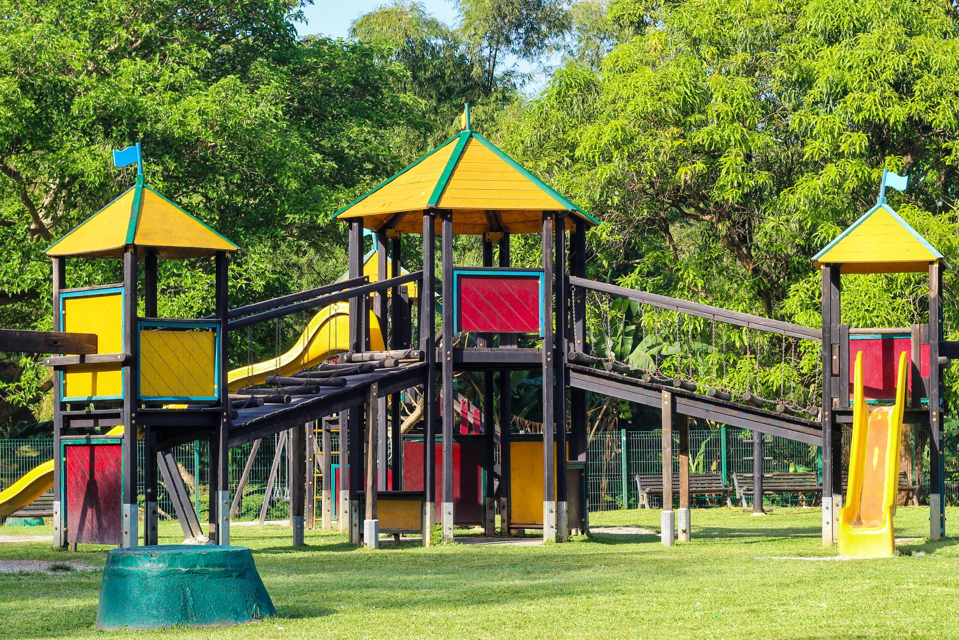 Outdoor playground surrounded by trees and green vegetation.
