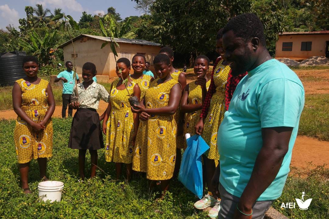 Girls in matching yellow dresses standing outdoors beside a man in a teal T-shirt, image 5 of 12